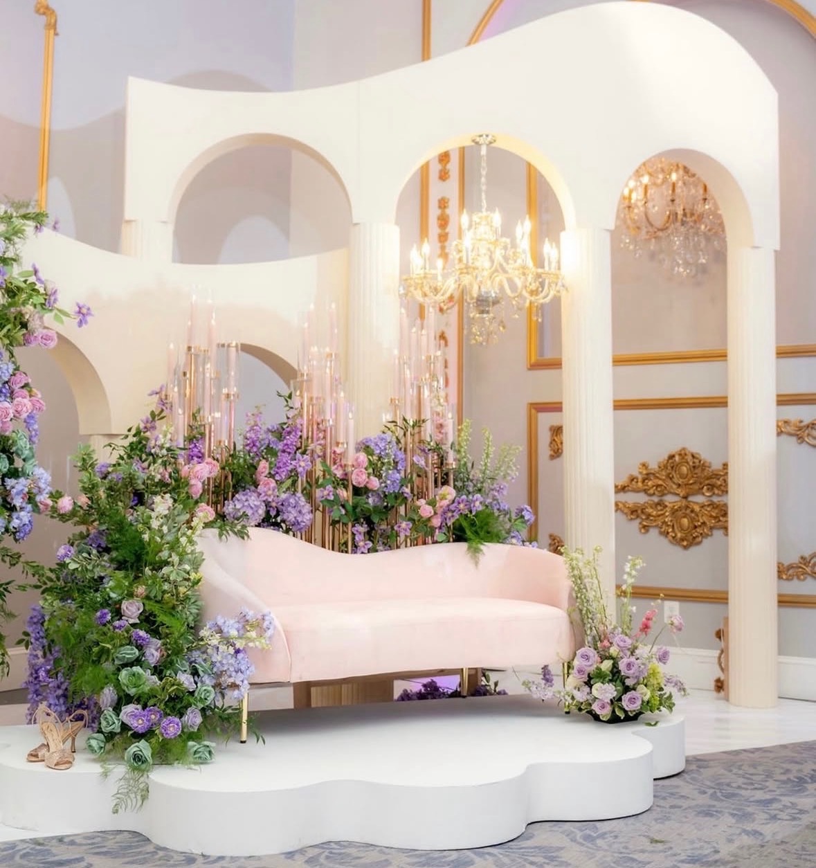 Elegant arch and floral party prop setup with pink sofa